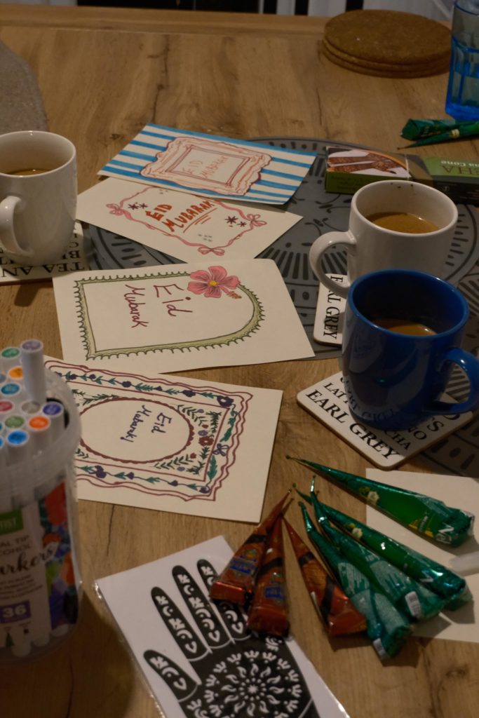 Handmade Eid artwork and cups of tea on a table.
