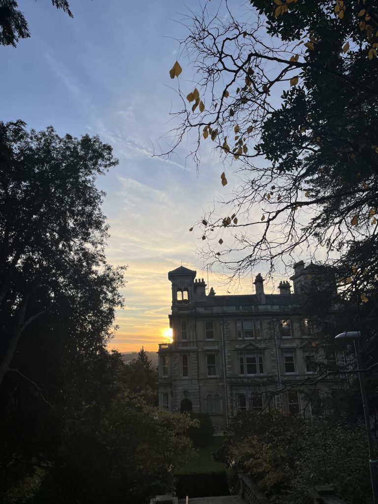 The sun setting behind a silhouetted Reed Hall building with a blue and orange sky.