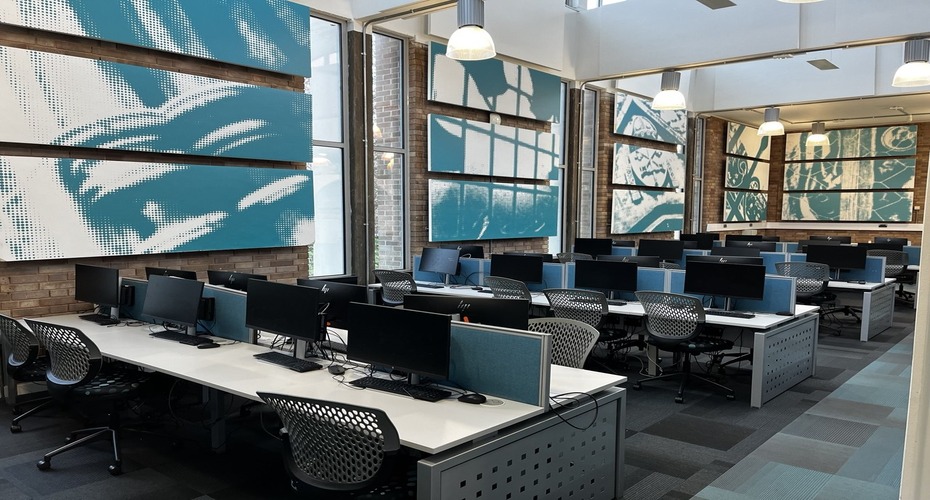 Open plan study space with desks, computers and chairs for students.