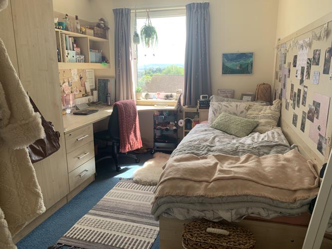 My en-suite bedroom in Lafrowda, decorated with cushions, photos and rugs.