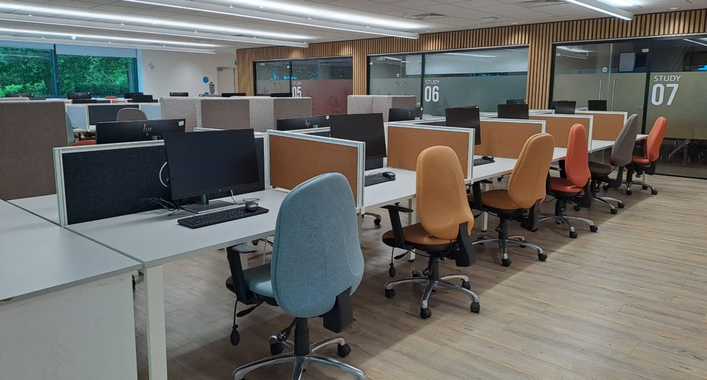 A room filled with rows of individual computer monitor cubicles