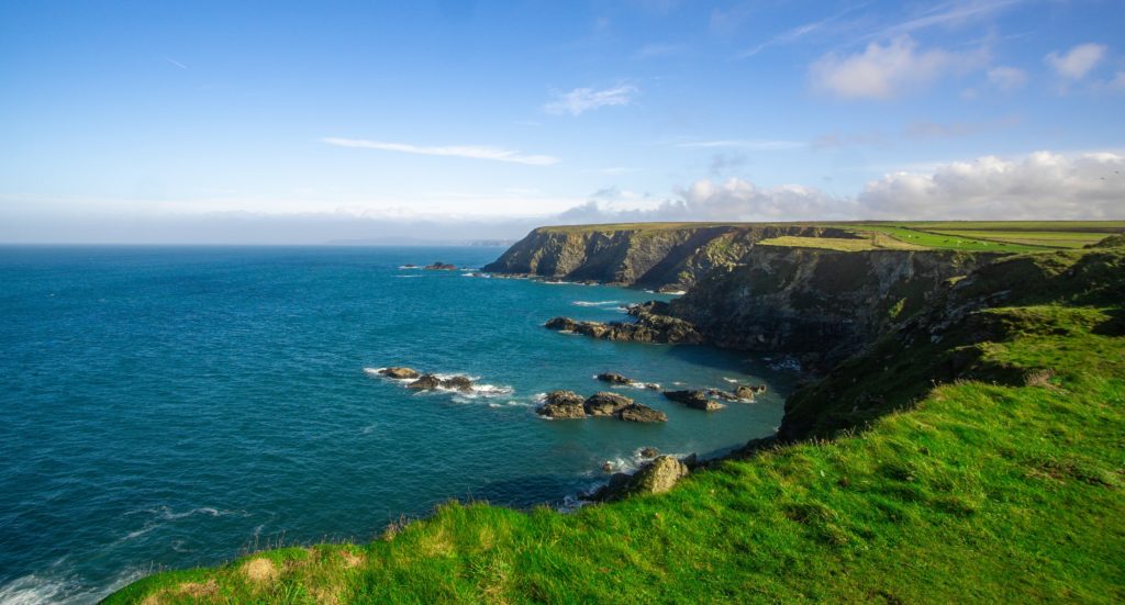 A scenic view of cliffs meeting the ocean under a clear sky in Cornwall