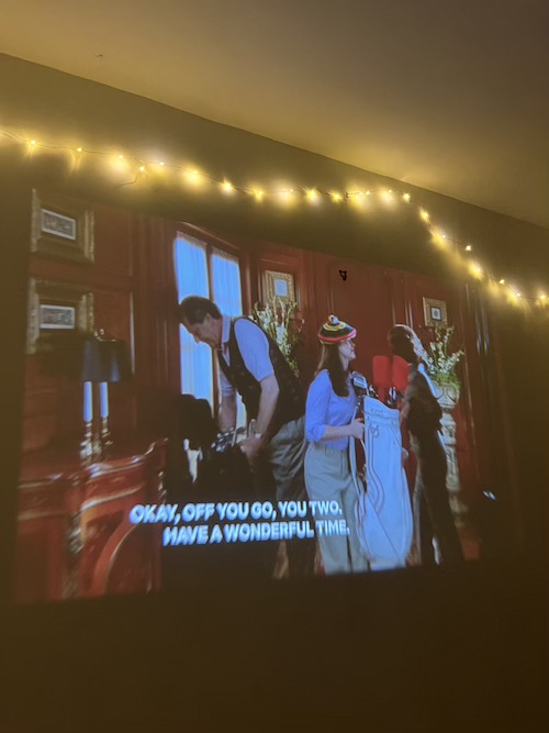A projection of the TV show Gilmore Girls on a wall with fairy lights