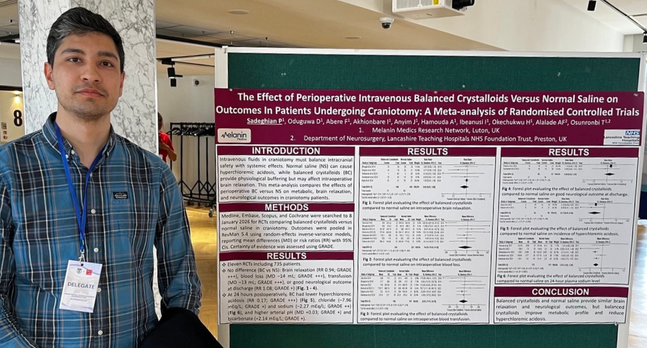 Pouria is standing next to a large poster with text and graphs relating to his research presentation.