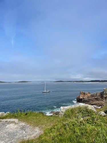 A small sail boat in the water with islands behind.