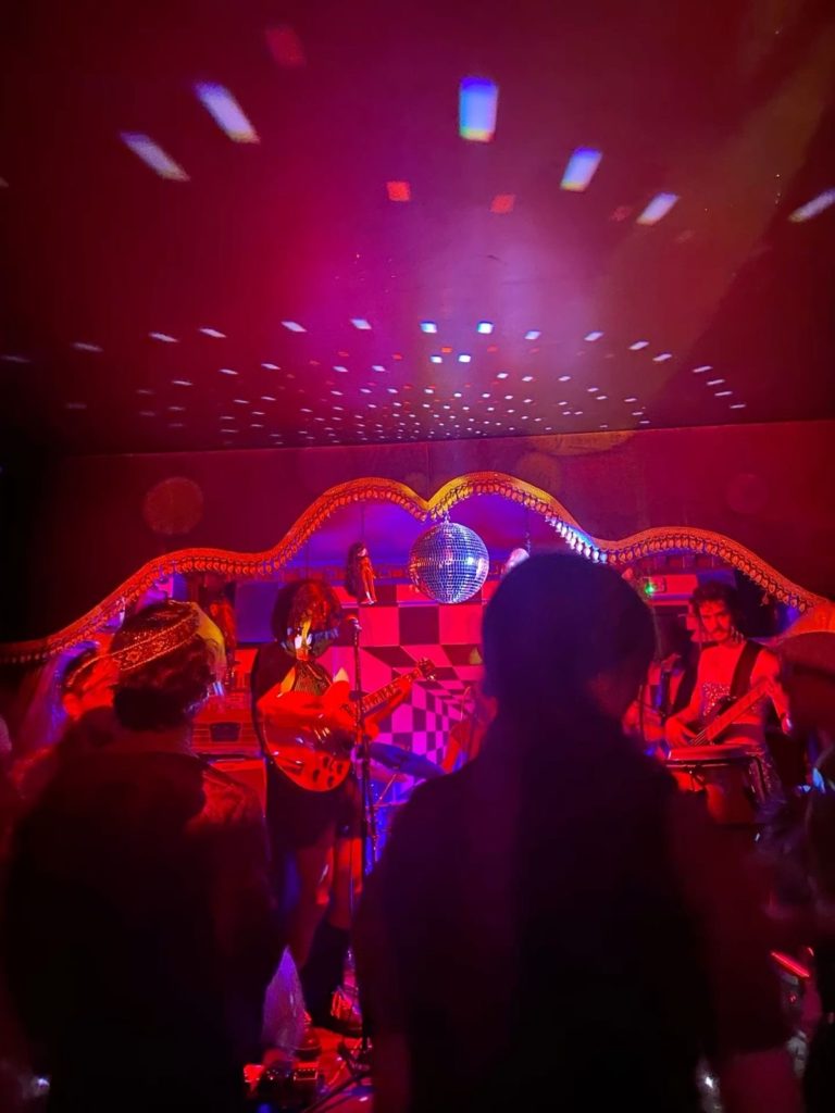 Band on stage with disco ball lighting.