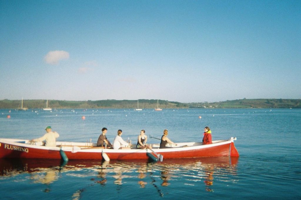 Gig rowing boat with crew inside out on the water.