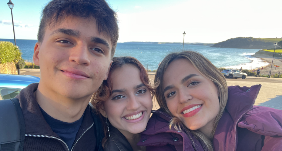 Three people taking a selfie with the beach behind them.