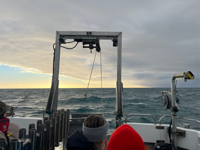 View from a boat of choppy sea, cloudy sky and sunset.